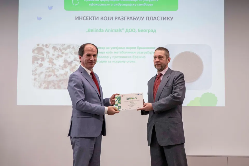 Yakup Beris, UNDP Resident Representative in Serbia, and Đorđe Veličković of Belinda Animals holding a recognition in front of the “Insects that break down plastic” presentation